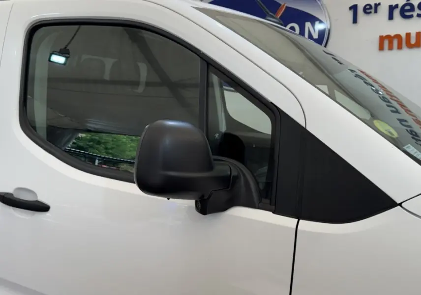 Vue latérale gauche rapprochée du Peugeot Partner blanc, mettant en valeur la porte et le rétroviseur noir.