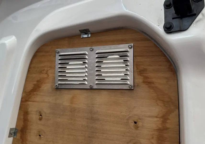 Gros plan sur la cloison en bois avec grille d’aération du Peugeot Partner blanc, vue intérieure arrière.