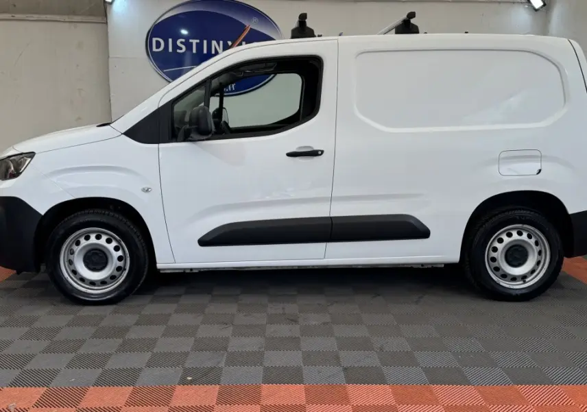 Vue de profil côté gauche d’un utilitaire Peugeot Partner blanc avec protections latérales noires et jantes acier.