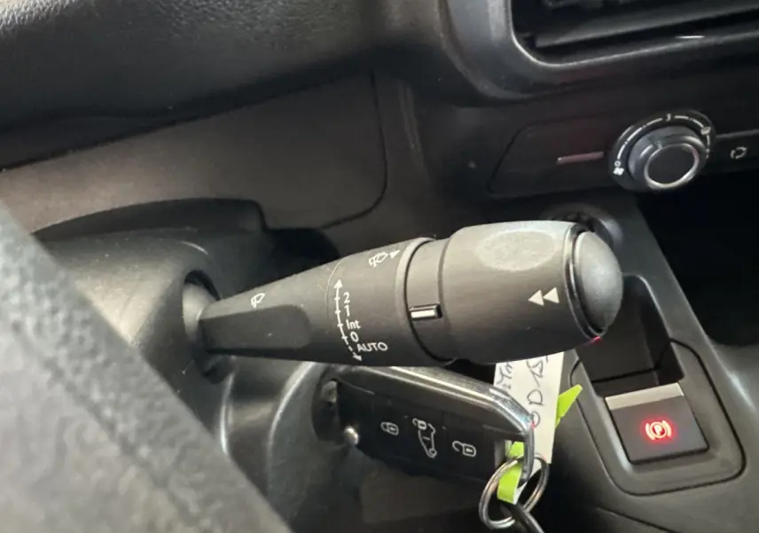 Gros plan sur la manette d’essuie-glace à gauche du volant dans l’habitacle noir du Peugeot Partner blanc.