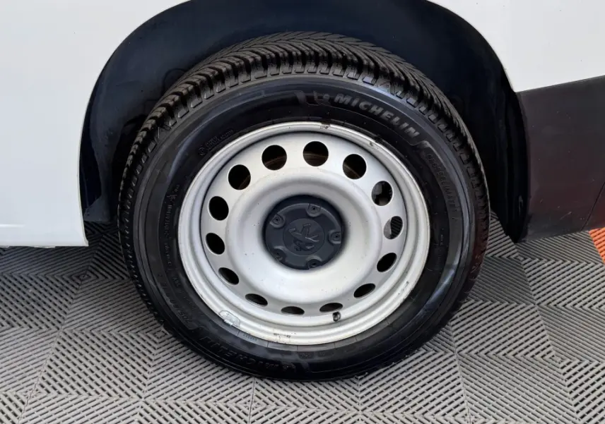 Gros plan sur la roue arrière droite en jante acier du Peugeot Partner blanc, avec pneu Michelin visible.