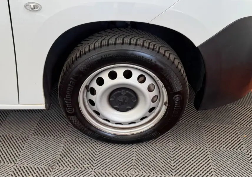 Gros plan sur la roue avant droite en jante acier du Peugeot Partner blanc, avec partie basse de la carrosserie visible.