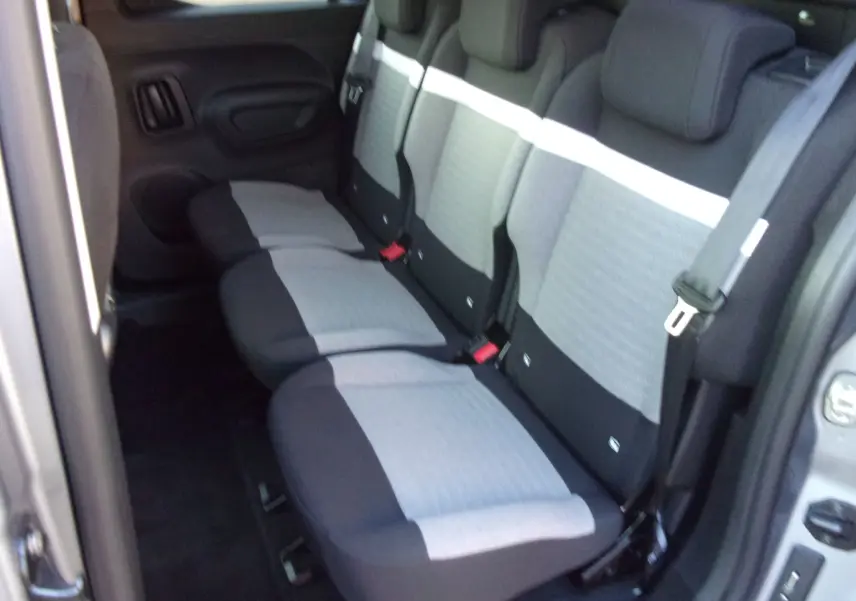 Vue intérieure arrière du Citroën Berlingo gris Artense, montrant les trois sièges arrière avec grille de séparation.