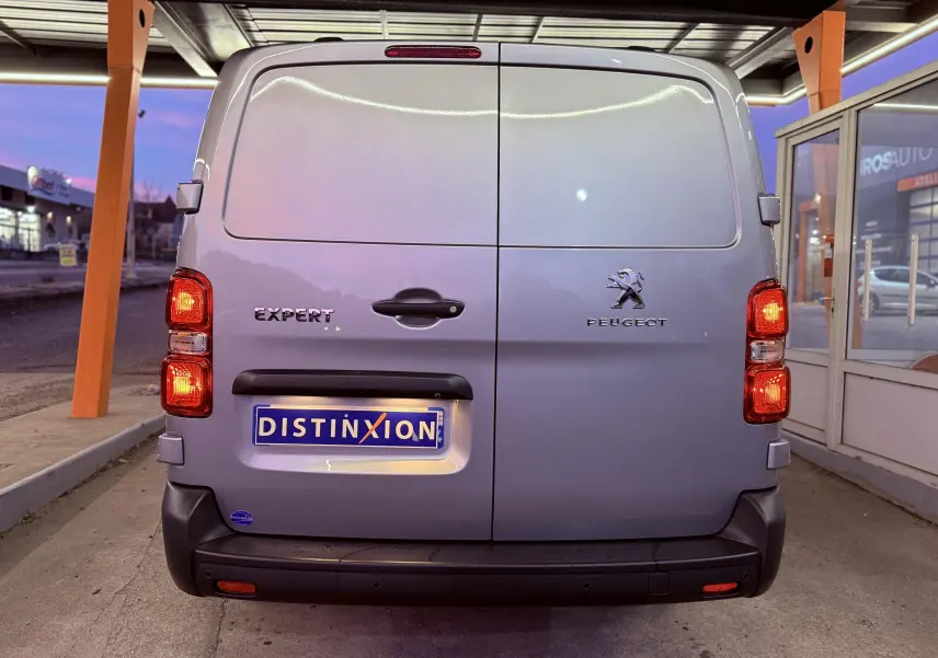 Vue arrière d’un Peugeot Expert Cabine Approfondie gris Artense métal avec feux allumés sous abri.