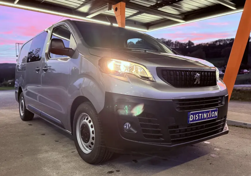 Peugeot Expert Cabine Approfondie gris Artense métal vu de 3/4 avant droit avec phare allumé sous abri au crépuscule.