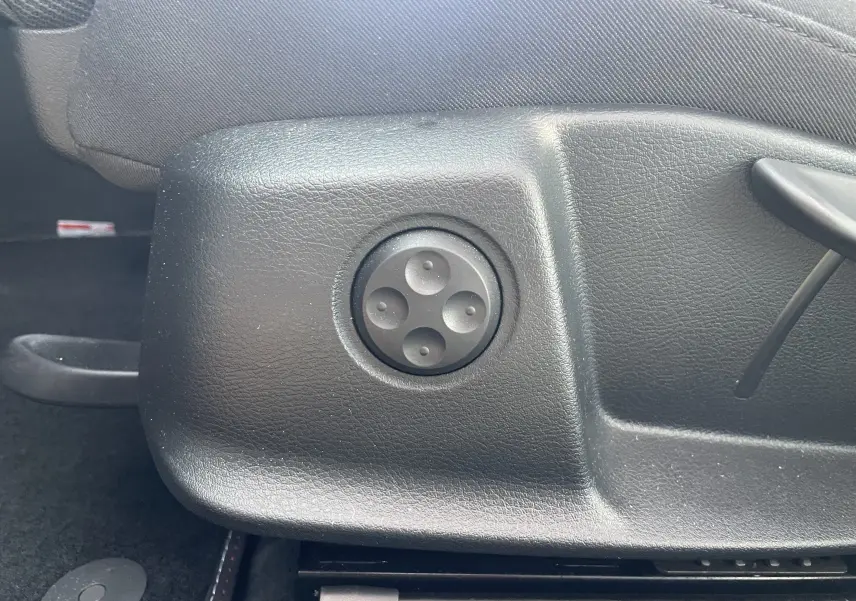 Gros plan sur la commande de réglage électrique du siège côté conducteur d'une Audi A4 Avant blanche de 2022.