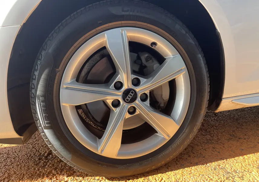 Gros plan sur la roue avant droite d'une Audi A4 Avant blanche 40 TDI 204 Quattro avec jante alliage cinq branches.