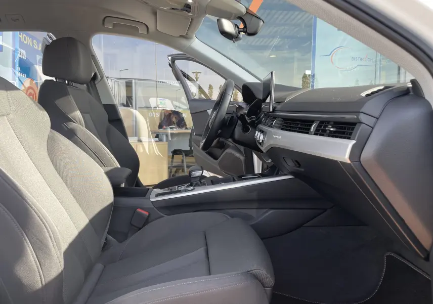 Intérieur côté conducteur d'une Audi A4 Avant blanc 2022, sièges tissu gris noir et tableau de bord moderne.