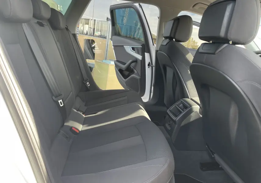 Vue intérieure arrière droite de l'Audi A4 Avant 40 TDI blanc, sièges tissu gris foncé et porte arrière ouverte.
