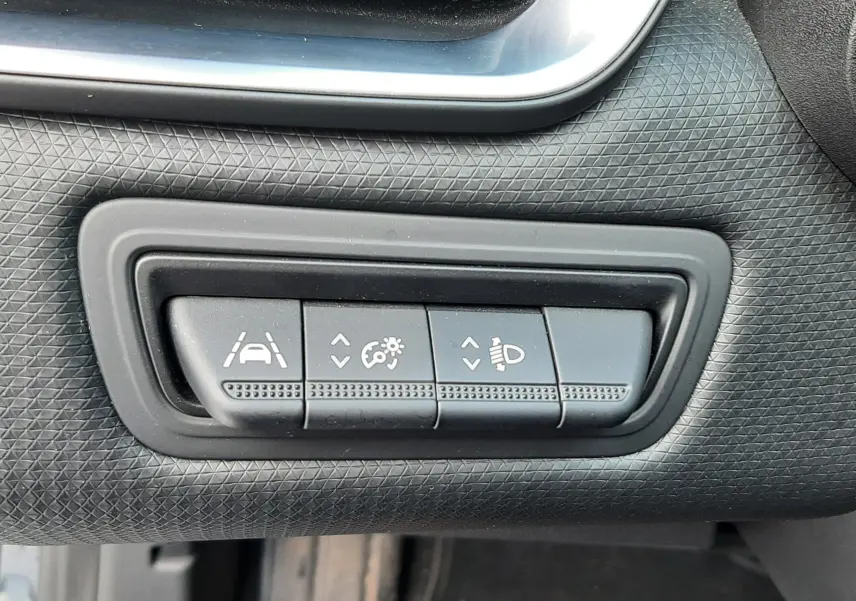 Gros plan sur les commandes de réglage d'assistance et d'éclairage dans l'habitacle d'une Renault Clio V gris titanium.