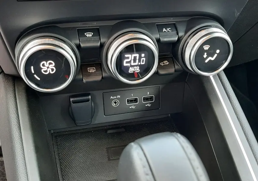 Gros plan sur la console centrale de la Renault Clio V gris titanium, montrant les commandes de climatisation et ports USB.