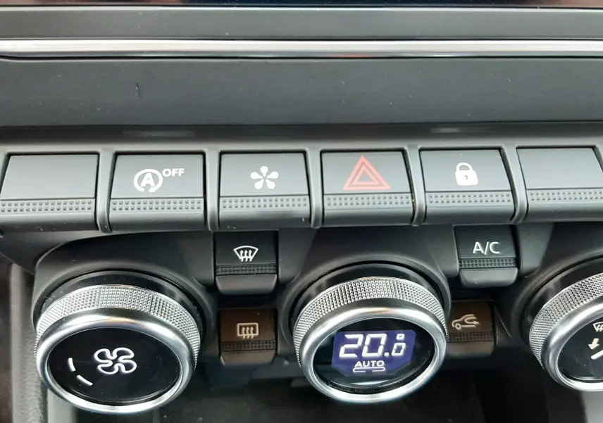 Gros plan sur les commandes de climatisation et boutons de fonction du tableau de bord d'une Renault Clio V gris titanium de 2021.