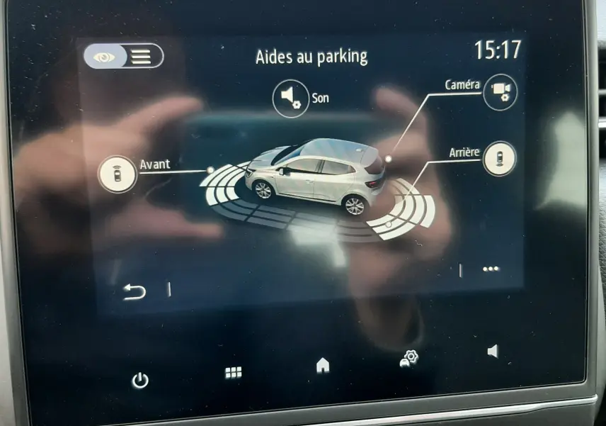 Écran tactile intérieur montrant l'aide au parking avec vue 3D d'une Renault Clio V gris titanium en stationnement.