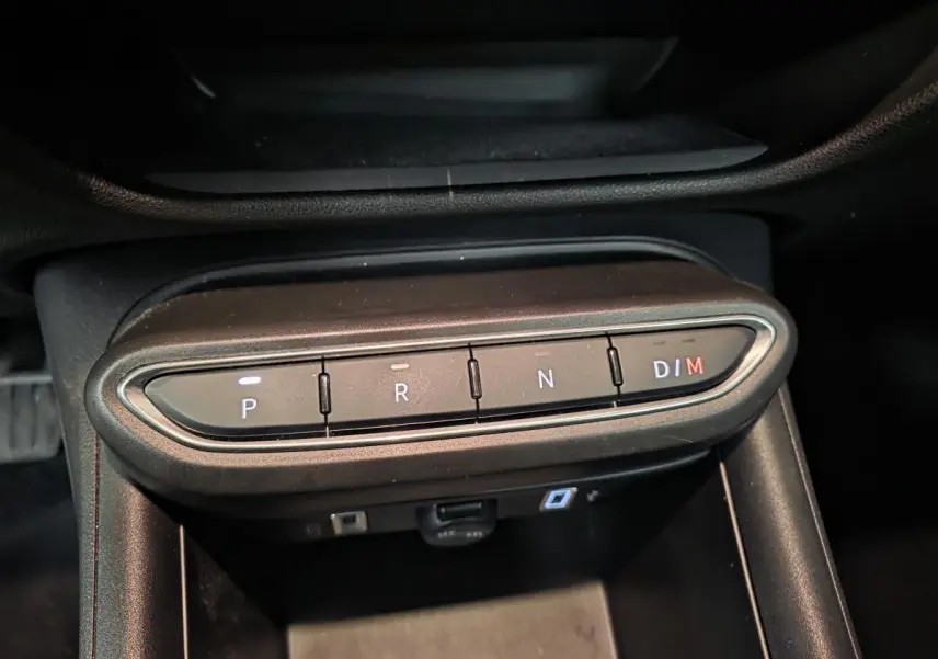 Gros plan sur les boutons de la boîte automatique de la FIAT 600 rouge, affichant les modes P, R, N et D/M.