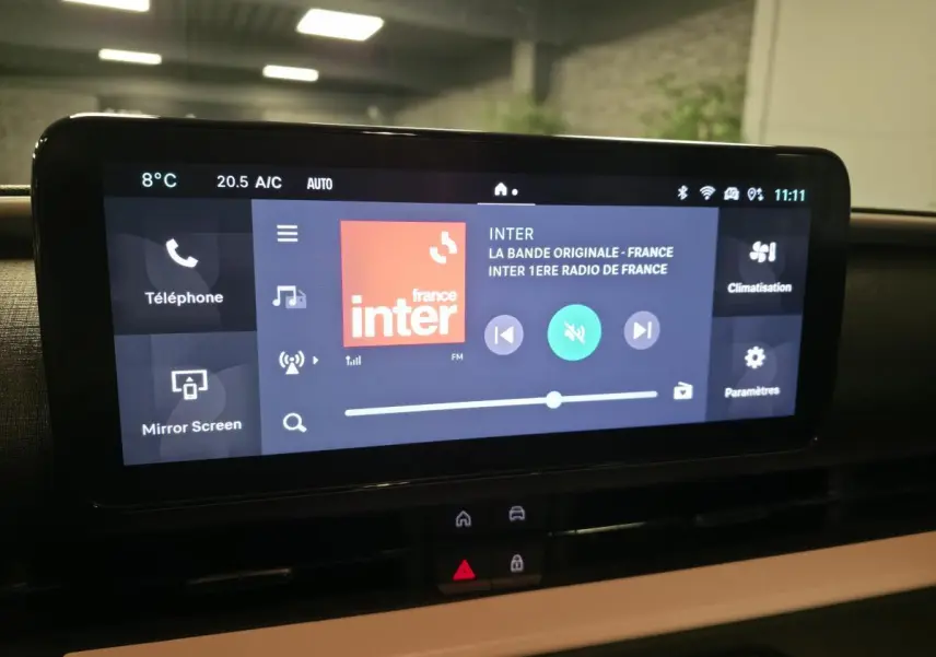 Écran tactile central du tableau de bord de la FIAT 600 rouge, affichant la radio France Inter en intérieur.