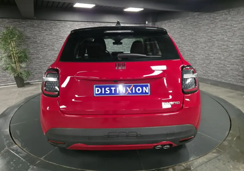 Vue arrière d'une FIAT 600 hybride rouge 2024 avec double sortie d'échappement côté droit et feux arrière LED noirs.