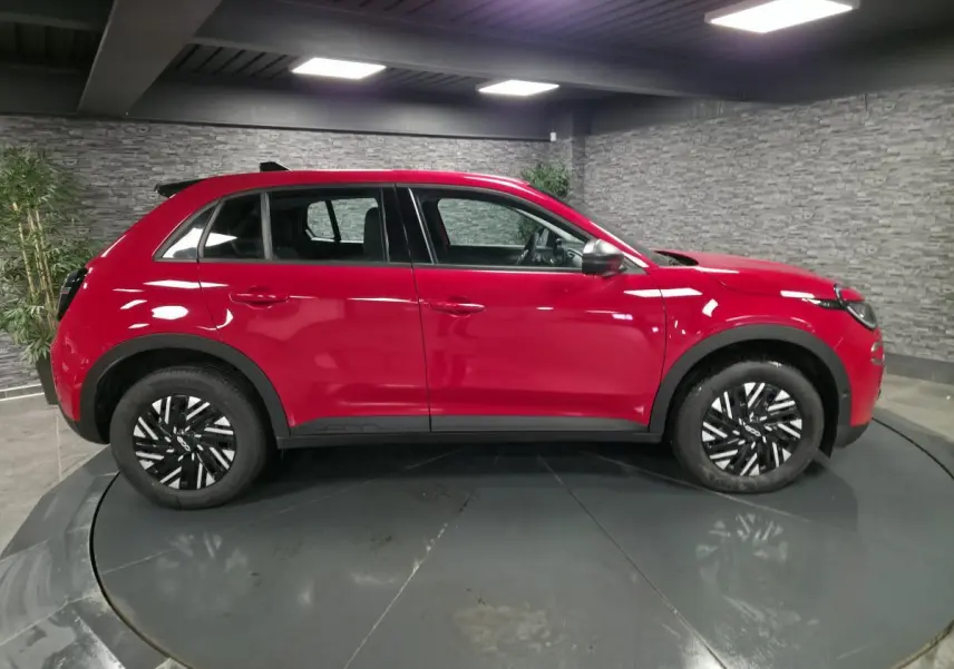 Vue de profil côté gauche d'une FIAT 600 rouge 2024 avec jantes noires et coques de rétroviseurs argentées.