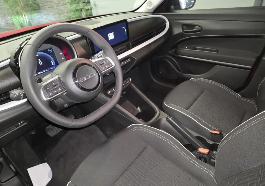 Intérieur avant de la FIAT 600 rouge 2024, vue côté conducteur avec tableau de bord numérique et volant Soft-Touch.