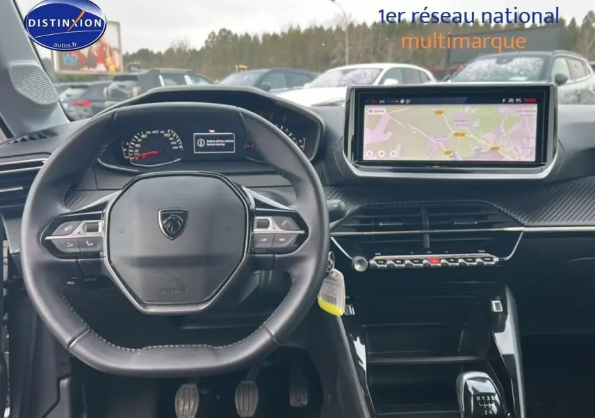 Vue intérieure frontale du poste de conduite de la Peugeot 208 gris artense, avec écran tactile et volant multifonction.