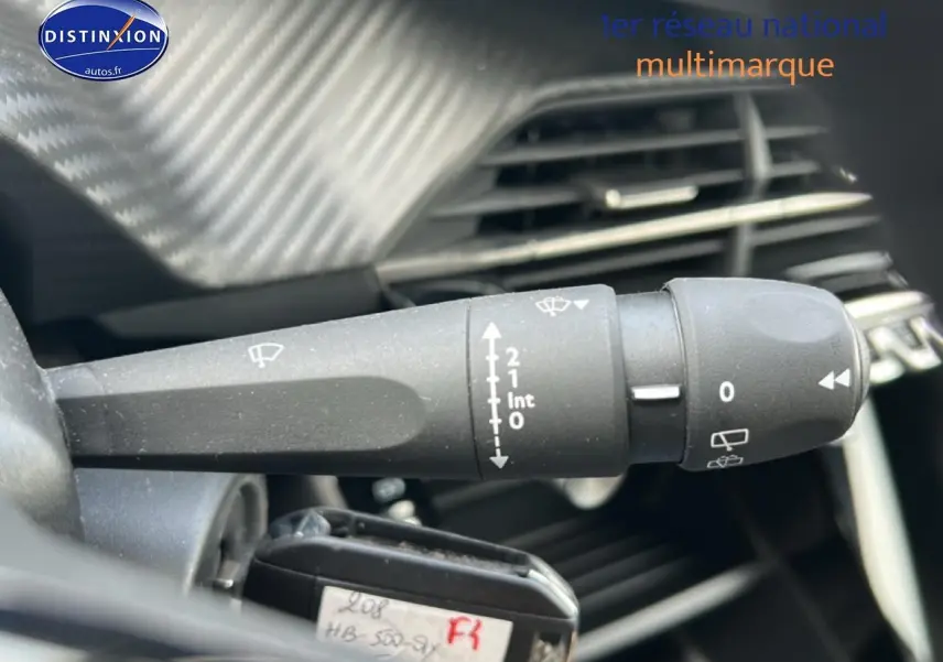Gros plan sur la commande d’essuie-glace côté gauche du tableau de bord d’une Peugeot 208 gris Artense 2025.