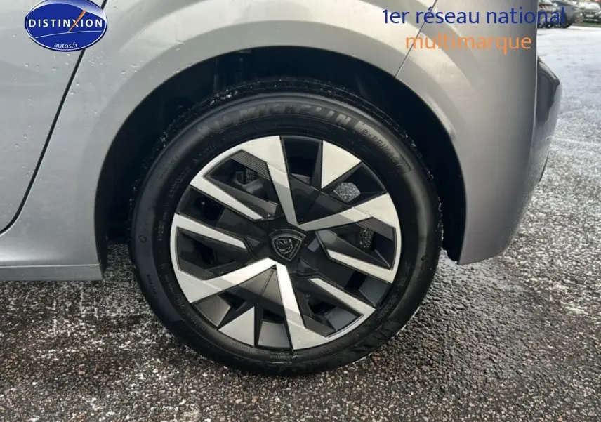 Gros plan sur la roue arrière droite gris artense d'une Peugeot 208 1.2 100 style avec jante au design géométrique.