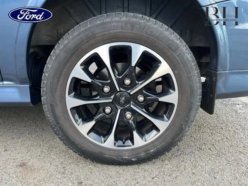 Gros plan sur la jante alu 17 pouces bicolore du côté avant droit du Ford Transit Custom Fourgon bleu azur métallisé.