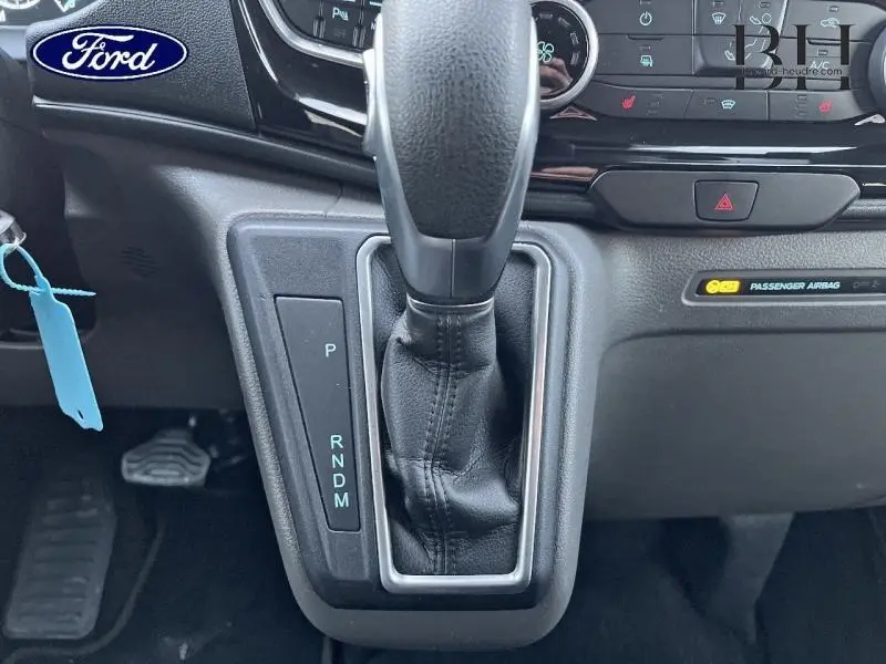 Gros plan sur le levier de vitesses automatique en cuir noir du Ford Transit Custom Fourgon, tableau de bord en arrière-plan.