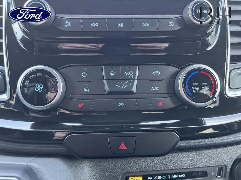 Gros plan sur la console centrale noire du Ford Transit Custom 2023, avec commandes climatisation et chauffage des sièges.