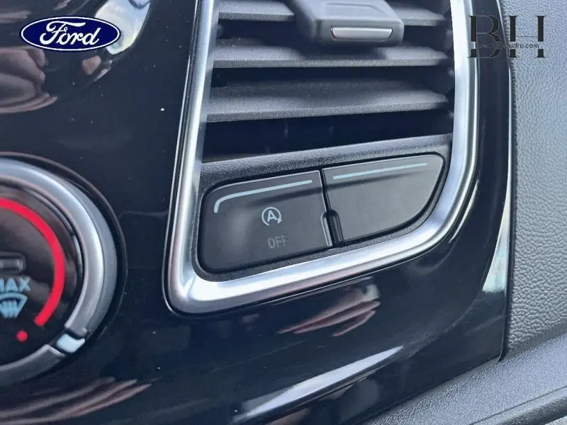 Gros plan sur le bouton d'arrêt du système start-stop dans l'habitacle noir du Ford Transit Custom bleu azur.