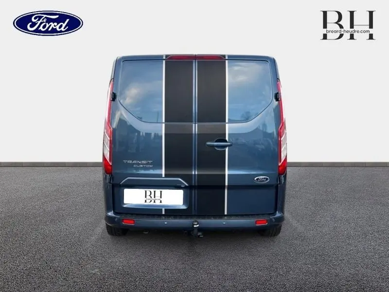 Vue arrière d'un Ford Transit Custom bleu azur métallisé avec bandes noires centrales et feux arrière rouges.