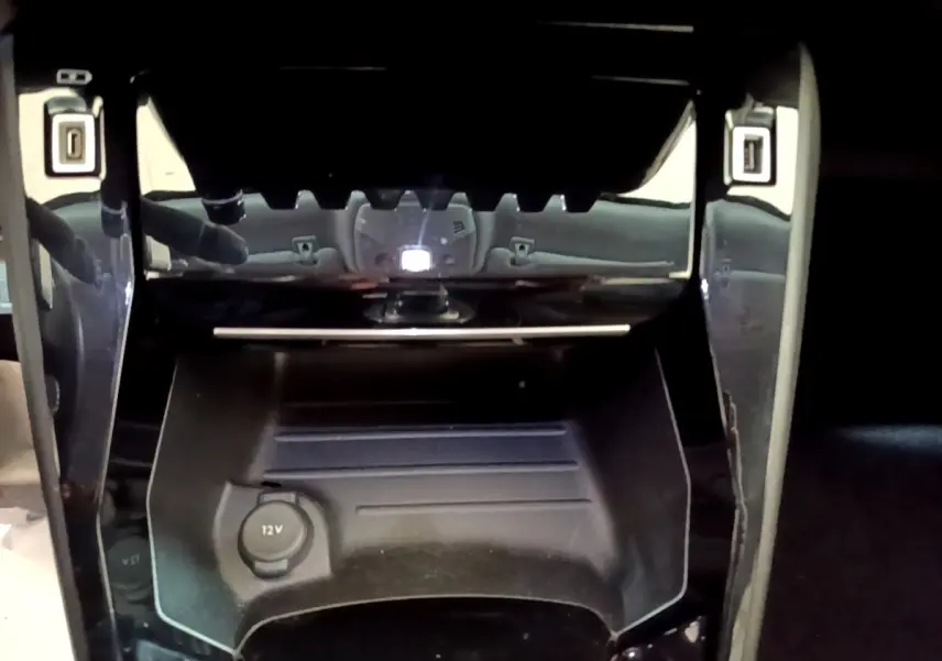 Prise 12V en gros plan dans la console centrale d’un Peugeot 2008 orange, version PureTech 130 Allure Business.