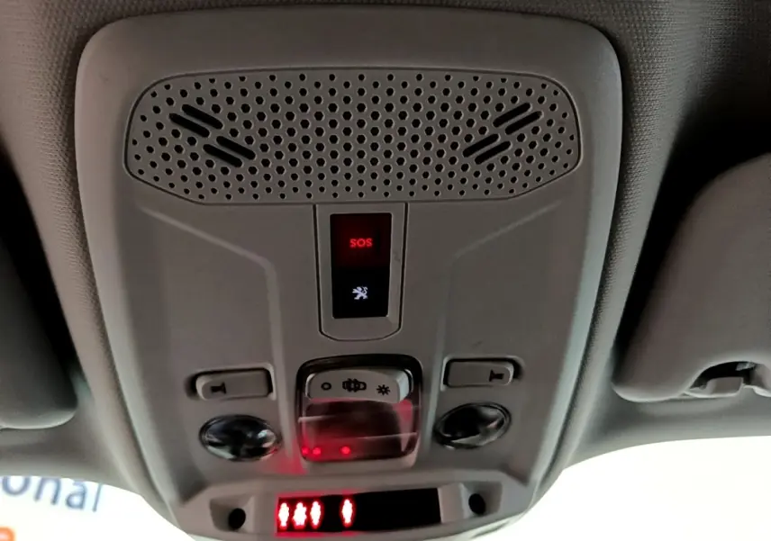 Vue en contre-plongée du panneau de commande intérieur au plafond avec bouton SOS rouge dans un Peugeot 2008 orange.