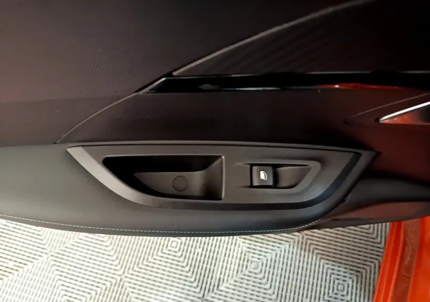 Gros plan sur la poignée intérieure et bouton de verrouillage de la porte côté gauche d’un Peugeot 2008 orange.