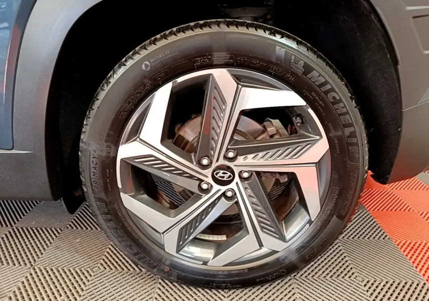 Gros plan sur la roue avant droite du Hyundai Tucson bleu, avec jante alliage au design géométrique moderne.