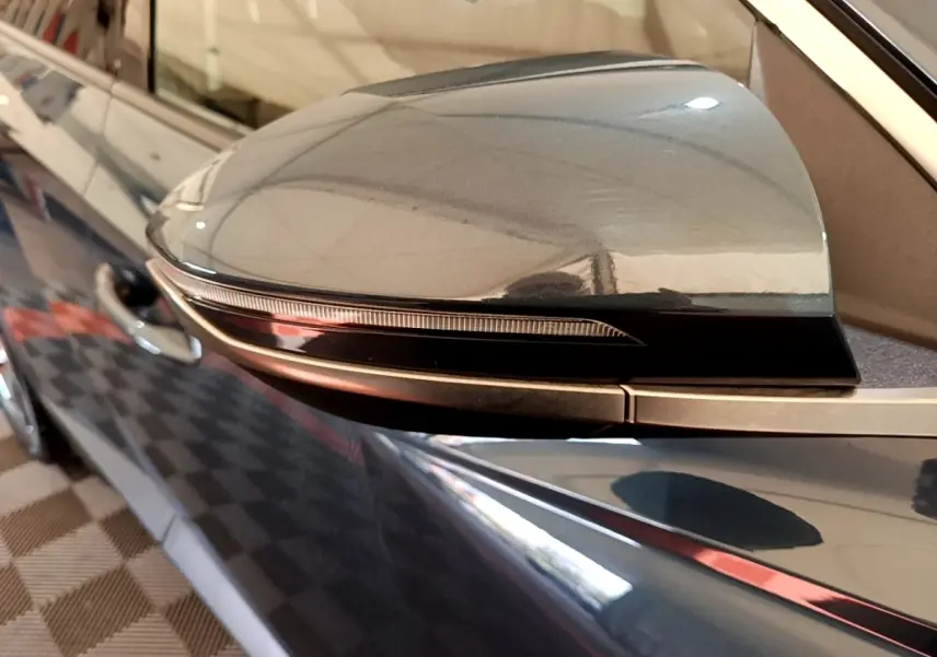 Gros plan sur le rétroviseur côté conducteur bleu du Hyundai Tucson 2023, avec clignotant intégré noir brillant.