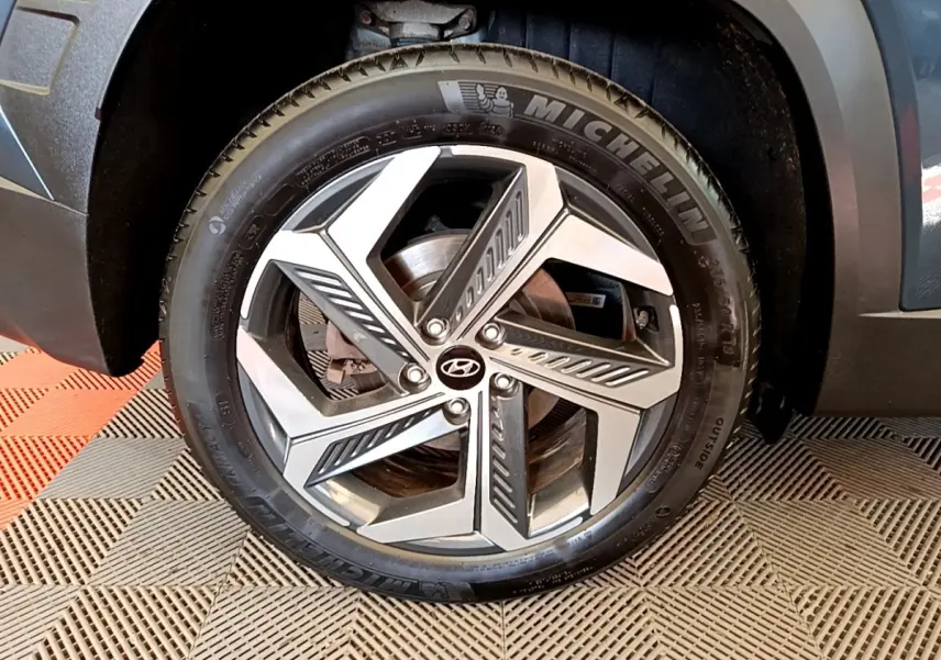 Gros plan sur la roue avant droite du Hyundai Tucson bleu, mettant en valeur la jante alliage moderne et le pneu Michelin.