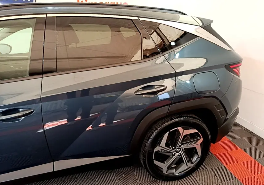 Vue côté droit arrière du Hyundai Tucson bleu 2023 avec jante alliage et feux arrière LED distinctifs.