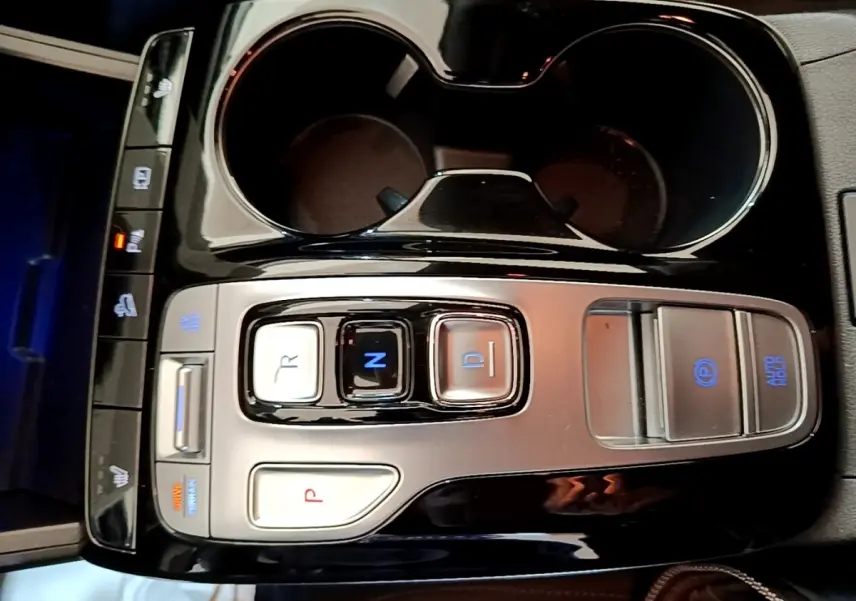 Vue rapprochée de la console centrale noire et argentée du Hyundai Tucson bleu avec commandes de boîte auto et frein électrique.