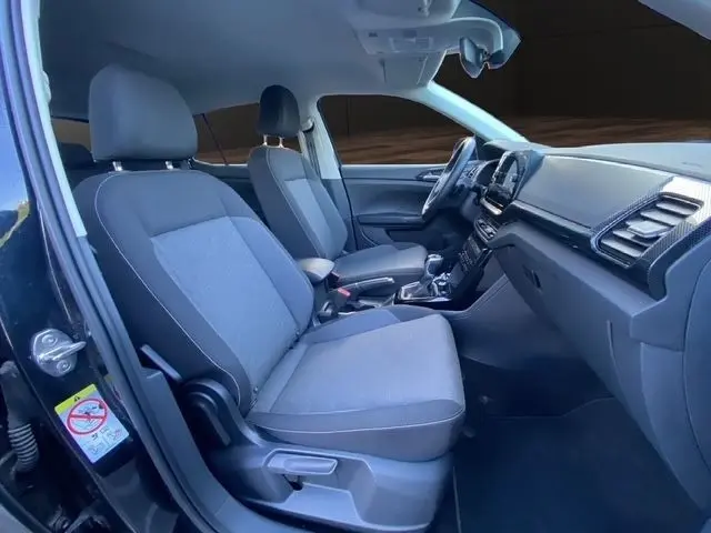 Vue intérieure côté conducteur du Volkswagen T-Cross noir 2025, montrant sièges tissu gris et tableau de bord moderne.