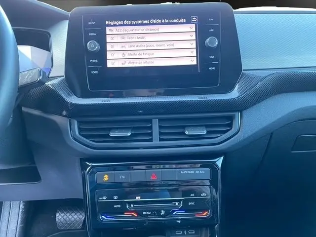 Vue rapprochée du tableau de bord noir du Volkswagen T-Cross 2025 avec écran tactile affichant les aides à la conduite.