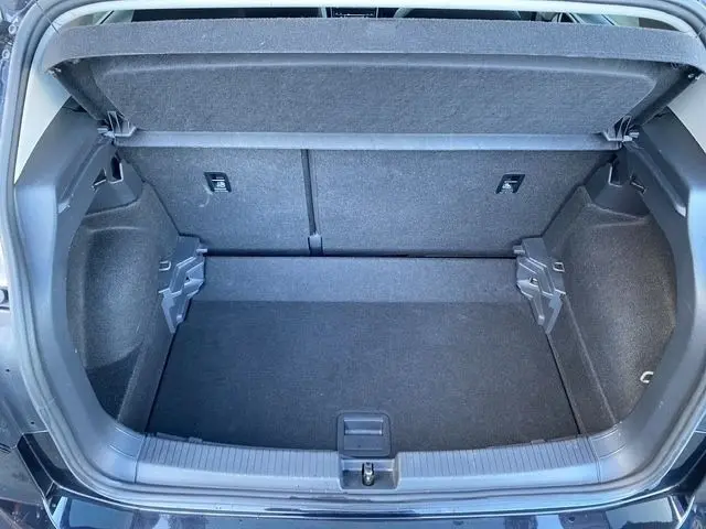 Coffre ouvert vu de l'arrière d'un Volkswagen T-Cross noir 2025, montrant un espace de rangement propre et spacieux.
