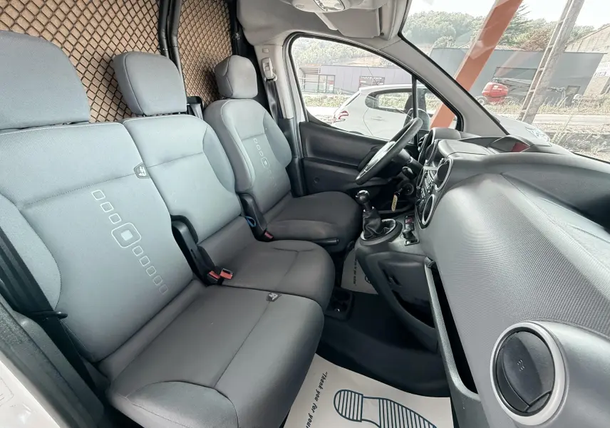 Vue intérieure côté conducteur du Citroën Berlingo 2016, montrant les sièges gris et le tableau de bord noir.