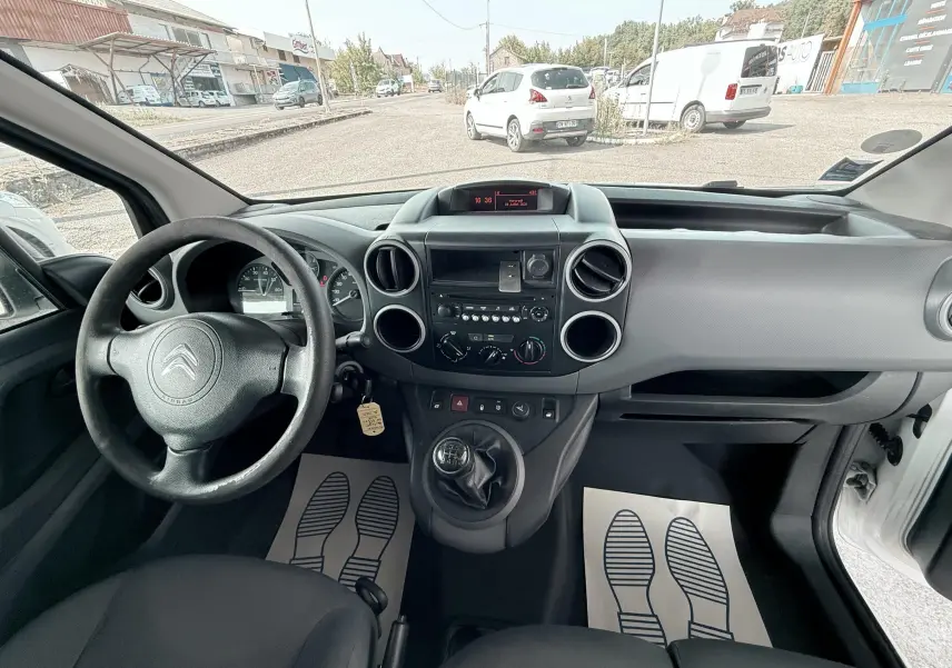 Vue intérieure du tableau de bord et volant côté gauche du Citroën Berlingo 2016 avec boîte manuelle et sellerie tissu noir.