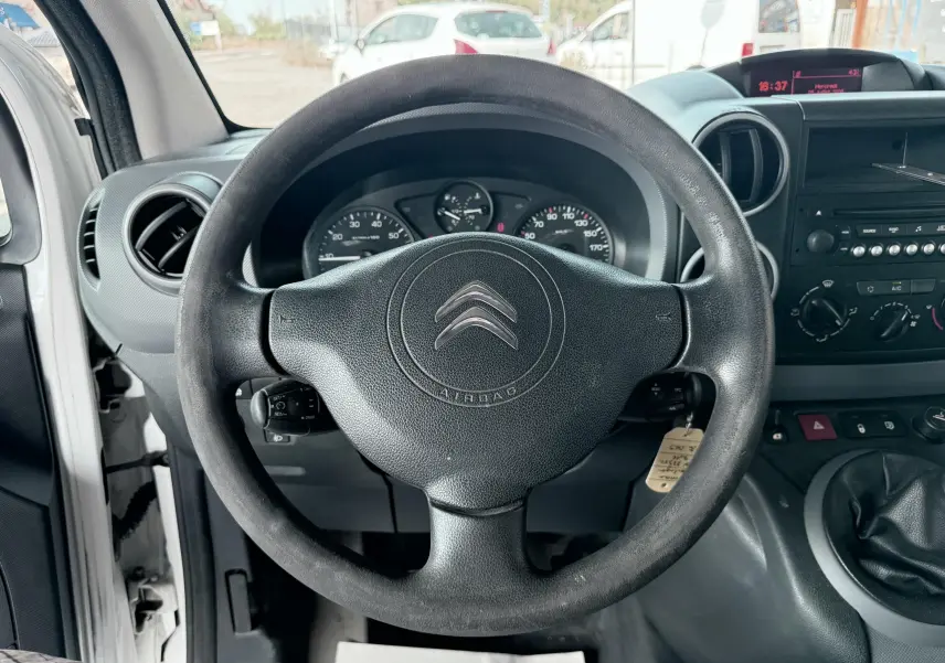 Vue intérieure centrée sur le volant noir du Citroën Berlingo blanc, avec tableau de bord et commandes visibles.