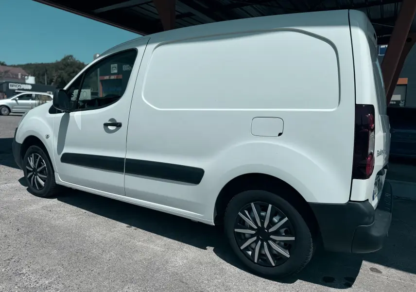 Vue de profil côté gauche du Citroën Berlingo blanc utilitaire avec protections latérales noires et jantes stylisées.