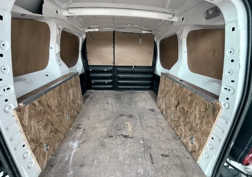Vue intérieure arrière du Citroën Berlingo blanc 2016, montrant l’espace de chargement avec plancher et panneaux en bois.