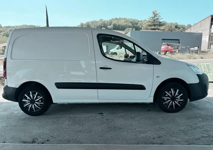 Vue de profil côté gauche d'un utilitaire blanc Citroën Berlingo 2016 avec jantes noires et baguettes latérales noires.