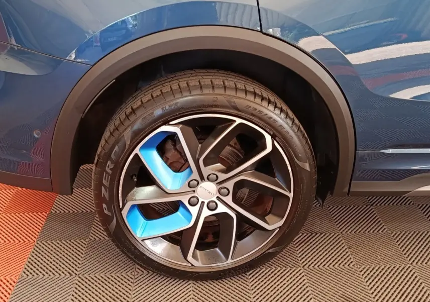 Gros plan sur la roue avant droite bleu et noire du SUV hybride rechargeable Link & Co 01 bleu 2023.