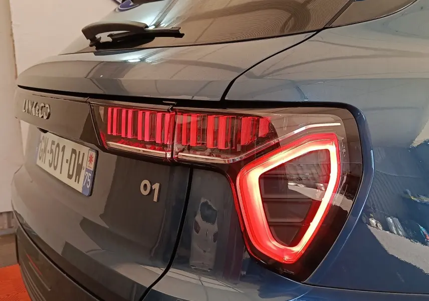 Vue arrière droite du SUV bleu LINK & CO 01 avec feux arrière LED allumés et logo visible sur le hayon.