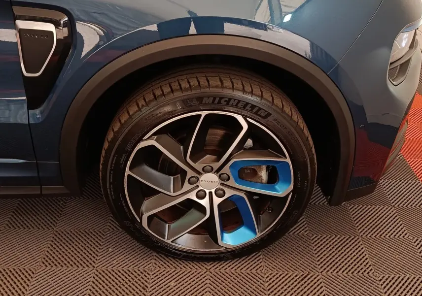Gros plan sur la roue avant gauche bleu métallisé du Lynk & Co 01 avec jante alliage bicolore et logo central.